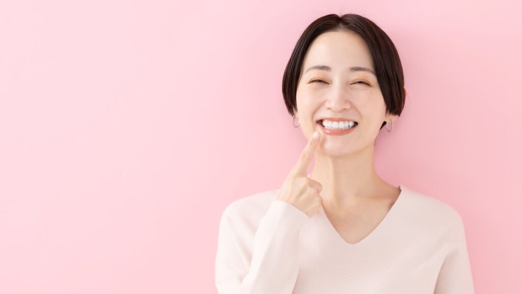 東京・銀座の街並みを背景に、ピンク色の健康な歯茎で自信を持って微笑む女性
