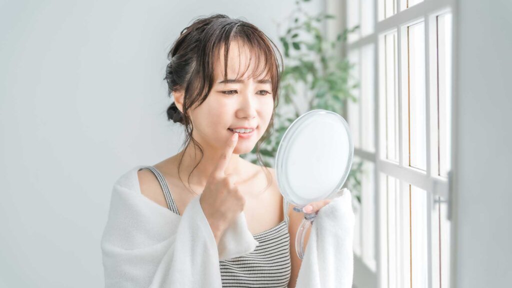 歯列矯正後の仕上がりに悩み、鏡の前でため息をつく東京・銀座の女性